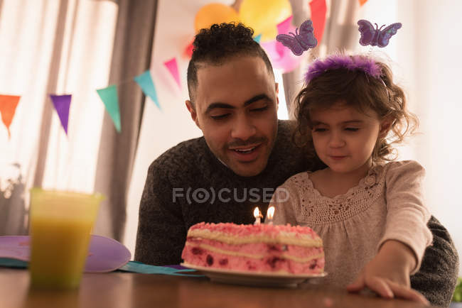 Padre e hija celebrando cumpleaños en la sala de estar en casa - foto de stock