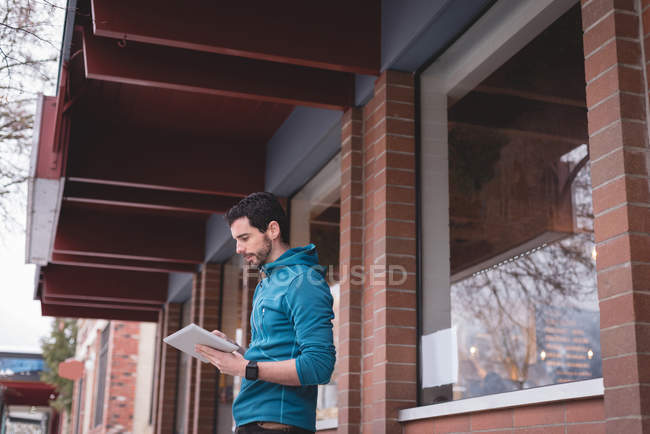 Young man using digital tablet outside the cafe — Stock Photo