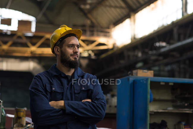 Thoughtful technician standing with arms crossed in metal industry — Stock Photo