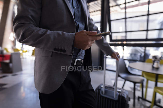 Mittelteil des Geschäftsmannes benutzt Smartphone beim Betreten des Hotels — Stockfoto