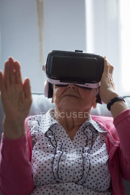 Mulher sênior usando fone de ouvido realidade virtual em casa — Fotografia de Stock
