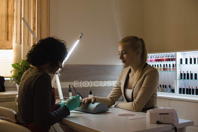 Esteticista dando tratamento de manicure para cliente feminino no salão — Fotografia de Stock
