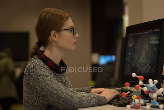 Молодая женщина с настольным компьютером в библиотеке — стоковое фото