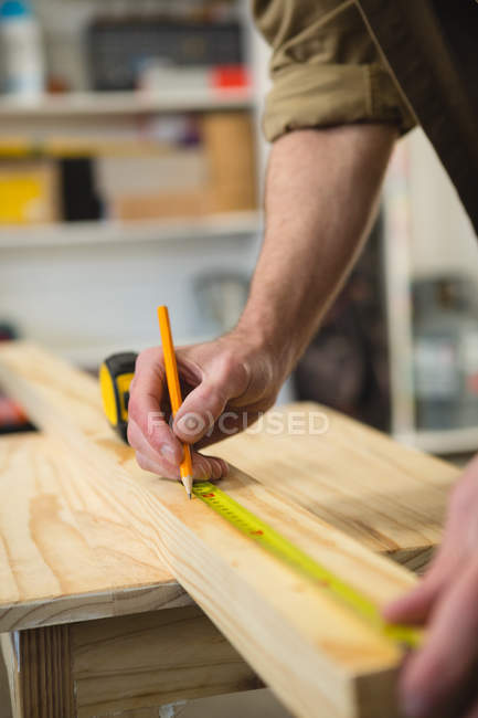 Seção média de carpinteiro masculino medição e marcação de madeira na oficina — Fotografia de Stock