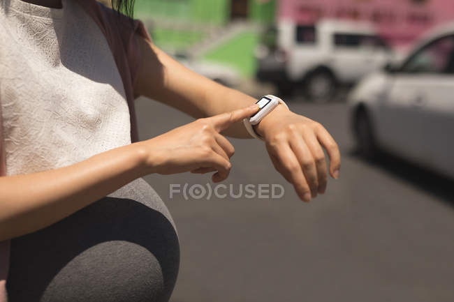 Schwangere nutzt Smartwatch an einem sonnigen Tag — Stockfoto