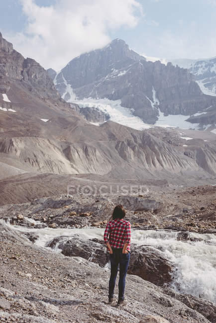 Жінка стоїть біля річки в сонячний день — стокове фото
