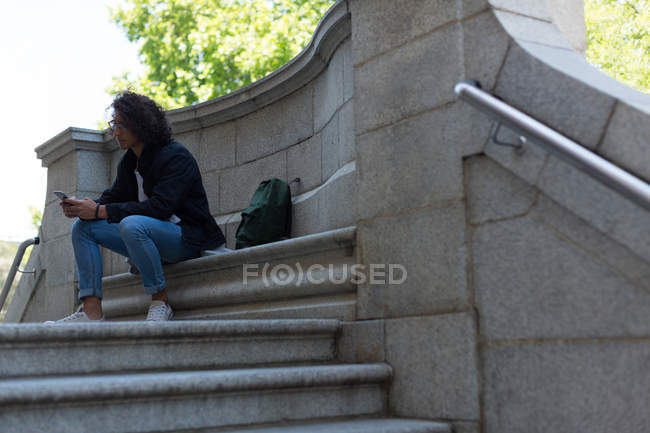 Молодой человек пользуется мобильным телефоном возле здания библиотеки — стоковое фото
