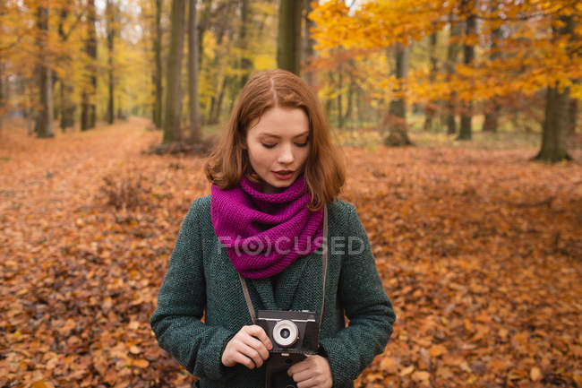 Donna che tiene la fotocamera vintage nel parco durante l'autunno — Foto stock