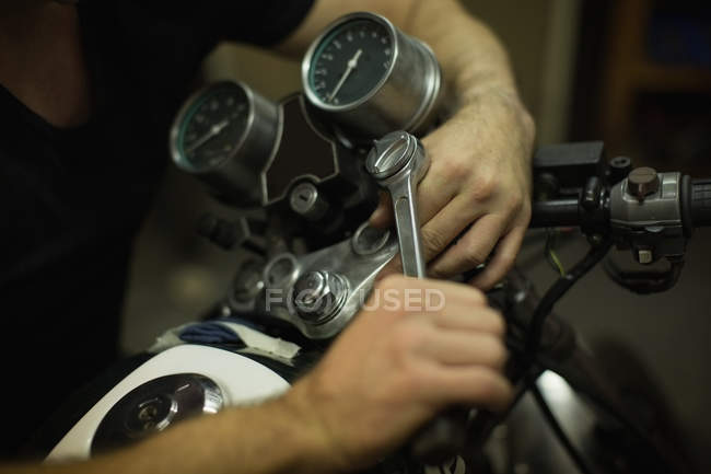 Mecánico apriete moto asa de bicicleta en el garaje - foto de stock