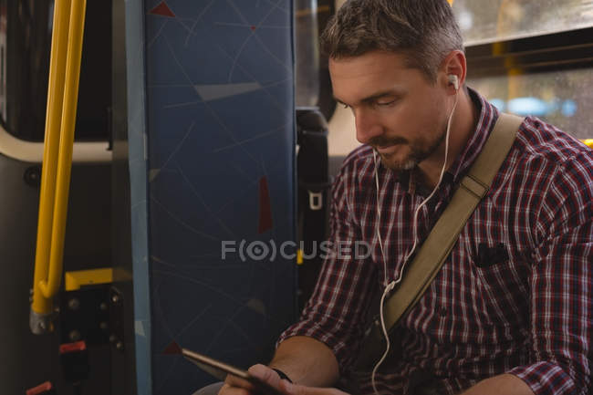 Mann hört während Straßenbahnfahrt Musik auf digitalem Tablet — Stockfoto