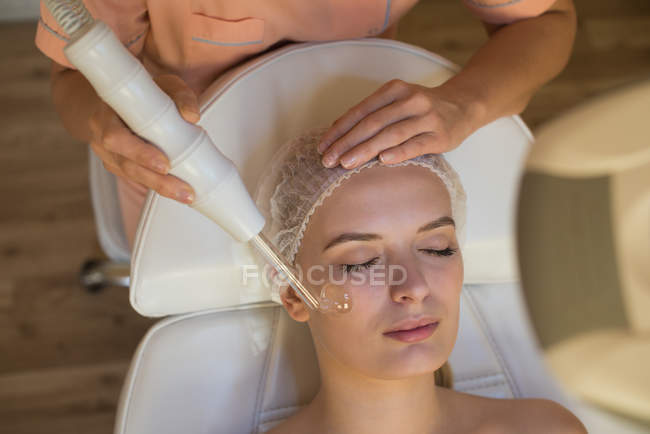 Beautician using a machine on female customer in parlour — Stock Photo