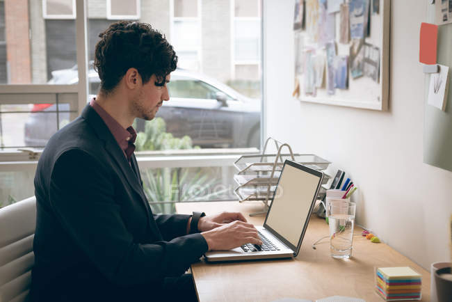 Executivo masculino trabalhando no laptop no escritório — Fotografia de Stock