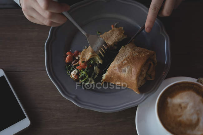 Primo piano della donna che mangia con cucchiaio e forchetta nel caffè — Foto stock