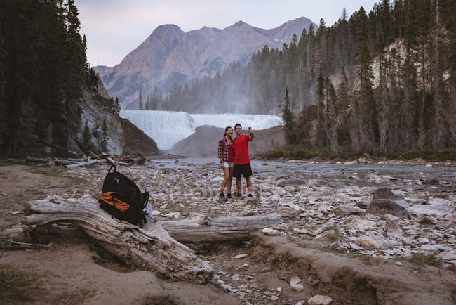 Paar macht Selfie mit Handy nahe Wasserfall — Stockfoto