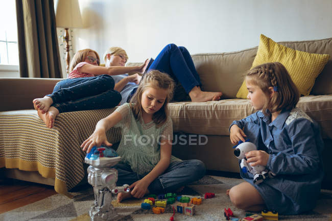 Irmãos brincando com brinquedos na sala de estar em casa — Fotografia de Stock