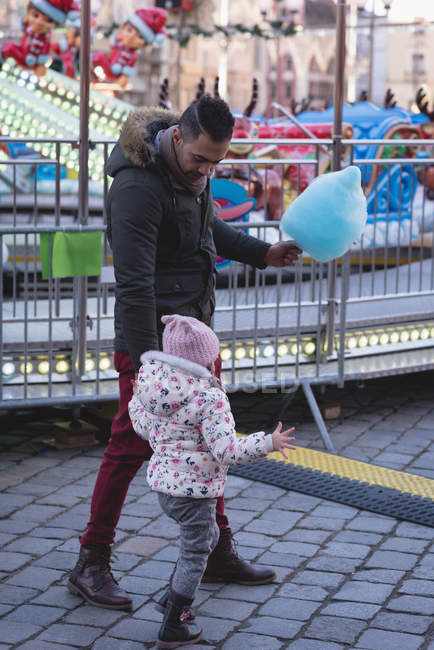 Батько і дочка гуляють з бавовняними цукерками в парку розваг — стокове фото