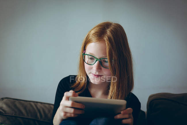 Chica atenta usando tableta digital en casa - foto de stock