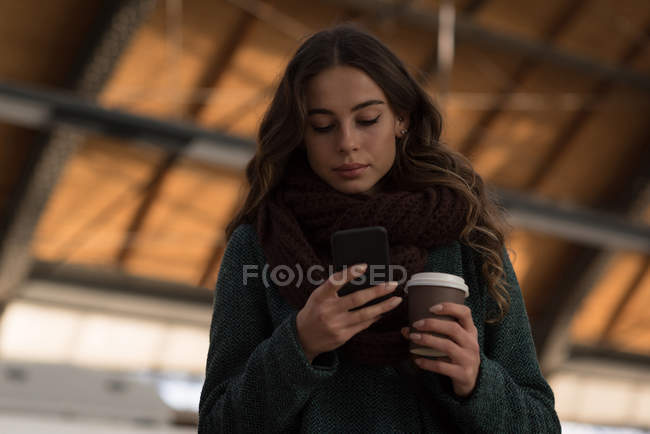 Молода жінка використовує мобільний телефон на залізничній станції — стокове фото