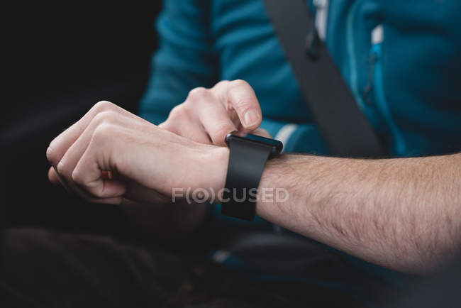 Sección media del hombre usando smartwatch en un coche - foto de stock