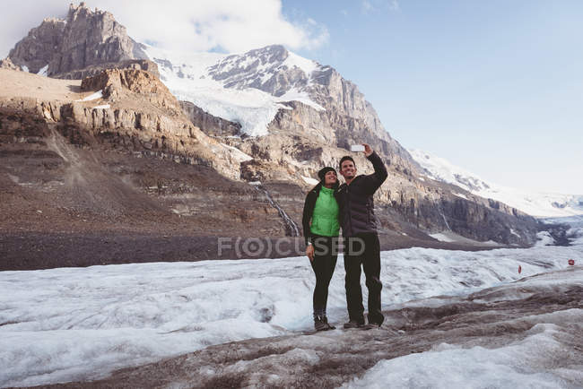 Пара бере селфі з мобільним телефоном біля гори — стокове фото