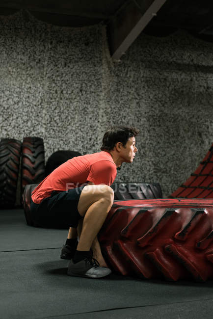 М'язистий чоловік підкидає шину в спортзалі — стокове фото