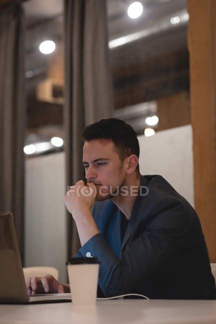 Young businessman using laptop in office — Stock Photo