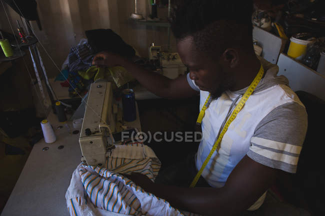 Tailor sewing clothes on sewing machine at shop — Stock Photo