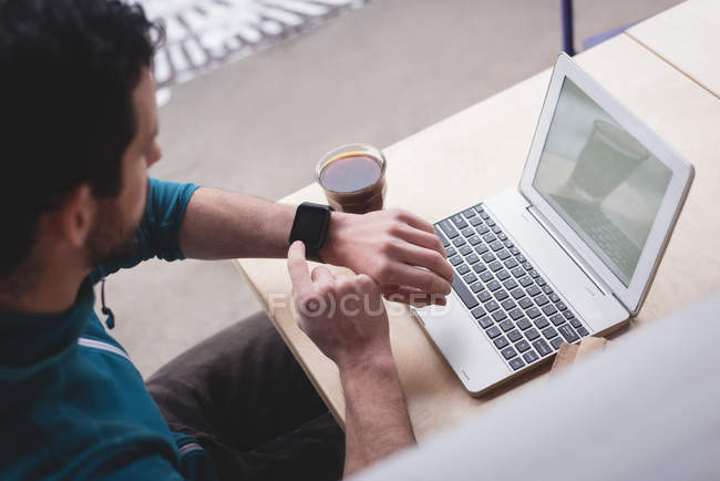Молодий чоловік використовує смарт-годинник у кафе — стокове фото
