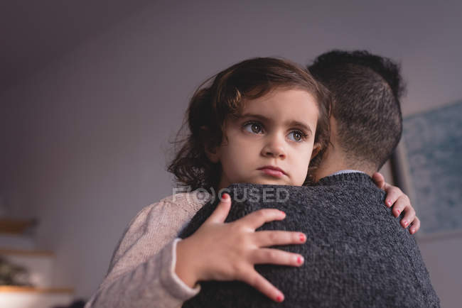 Батько обіймає доньку у вітальні вдома — стокове фото