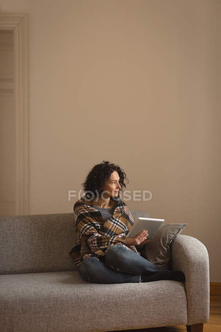 Mujer usando tableta digital en la sala de estar en casa - foto de stock