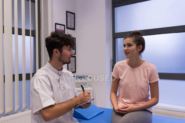 Female patient interacting with physiotherapist in clinic — Stock Photo