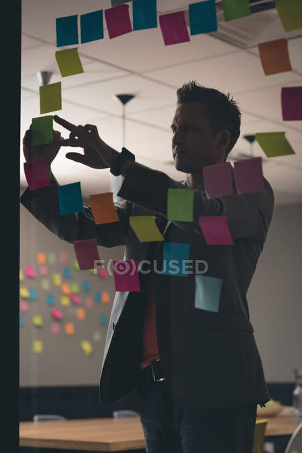 Empresário escrevendo em notas pegajosas no escritório — Fotografia de Stock