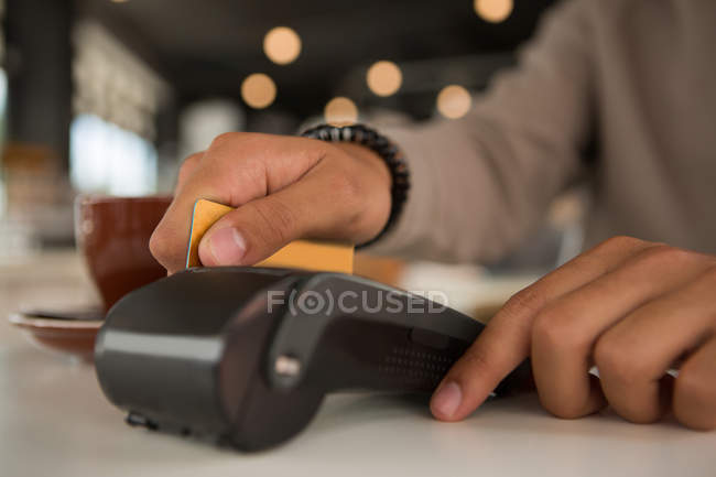 Hombre haciendo el pago a través de tarjeta de débito en cafetería - foto de stock
