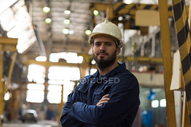 Retrato del técnico confiado de pie con los brazos cruzados en la industria del metal - foto de stock