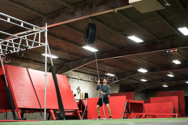 Мускулистый мужчина тренируется с шиной в спортзале — стоковое фото