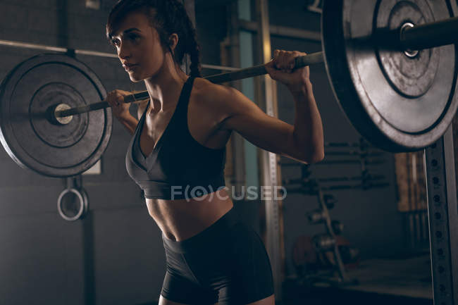 Fit woman lifting the barbell in the gym — Stock Photo