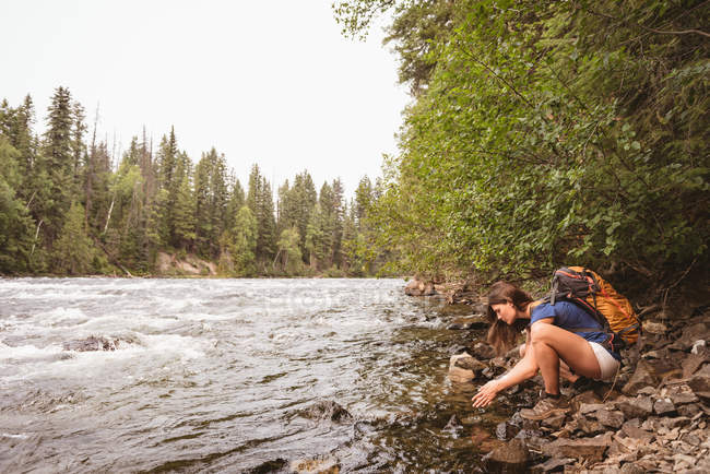 Вид сбоку женщины, моющей руку в реке — стоковое фото