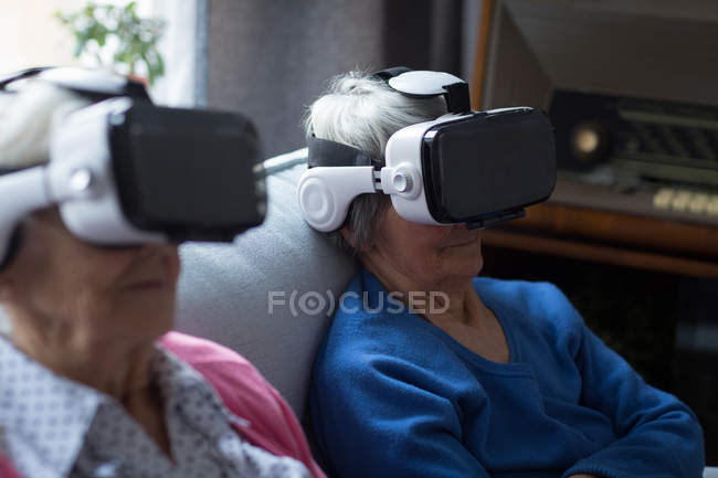 Senior friends using virtual reality headset at home — Stock Photo