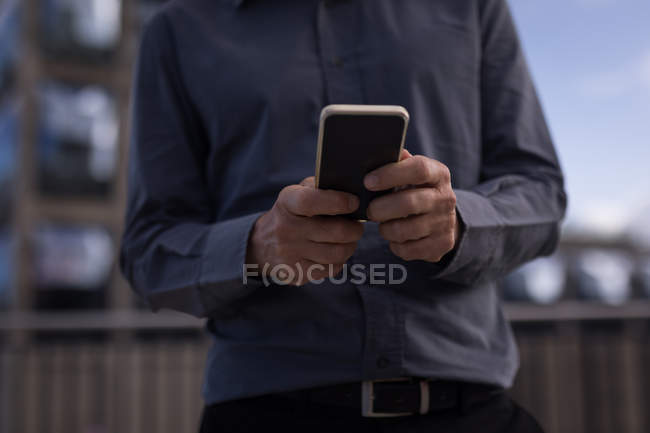 Mid section of businessman holding mobile phone in hotel premises — Stock Photo