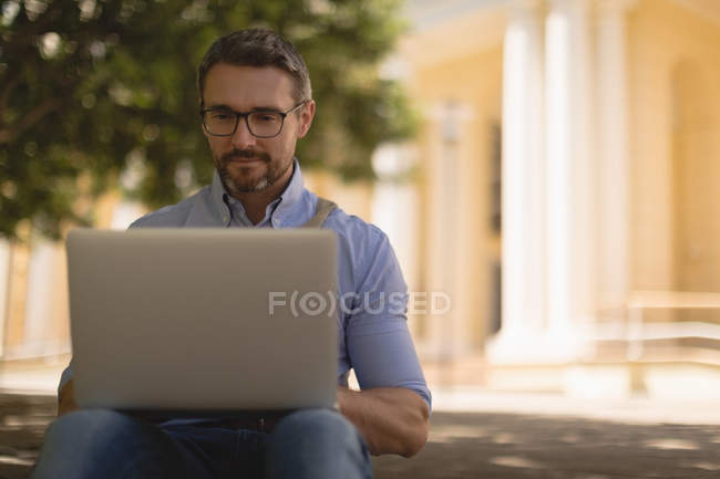 Uomo che utilizza il computer portatile nel parco in una giornata di sole — Foto stock