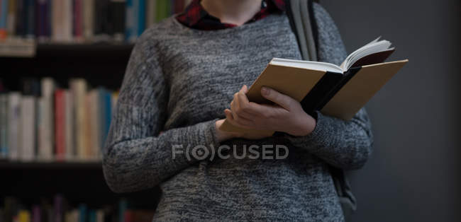 Seção intermediária da jovem mulher lendo um livro na biblioteca — Fotografia de Stock