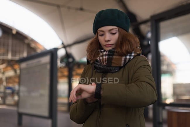 Красивая женщина в зимней одежде смотрит на умные часы — стоковое фото