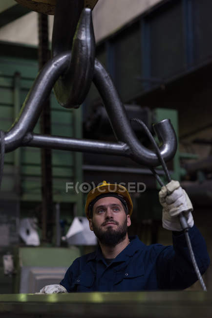 Внимательный техник, регулирующий металлическое оборудование на крючок — стоковое фото