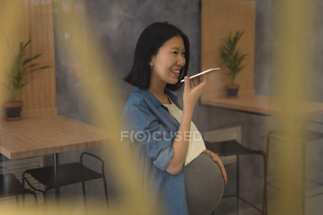 Pregnant businesswoman talking on mobile phone in office — Stock Photo