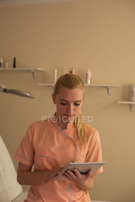Young female beautician using digital tablet in parlour — Stock Photo