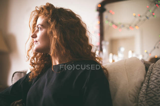Продумана жінка сидить на дивані у вітальні вдома — стокове фото