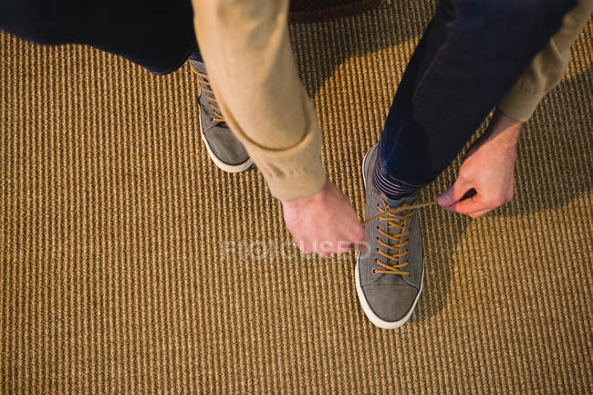 Low section of man tying shoelaces in living room at home — Stock Photo