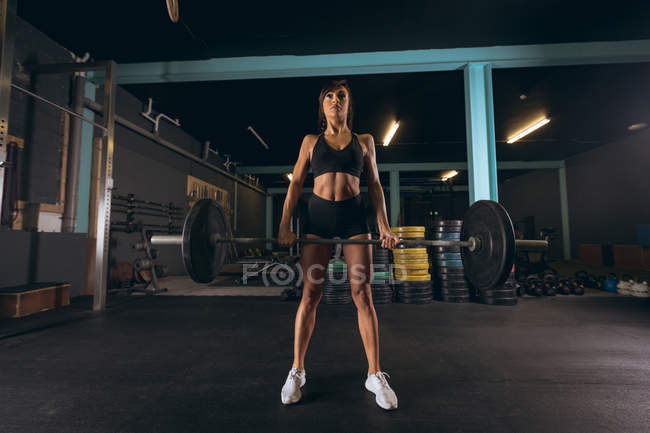 Fit femme levant le haltère dans la salle de gym — Photo de stock