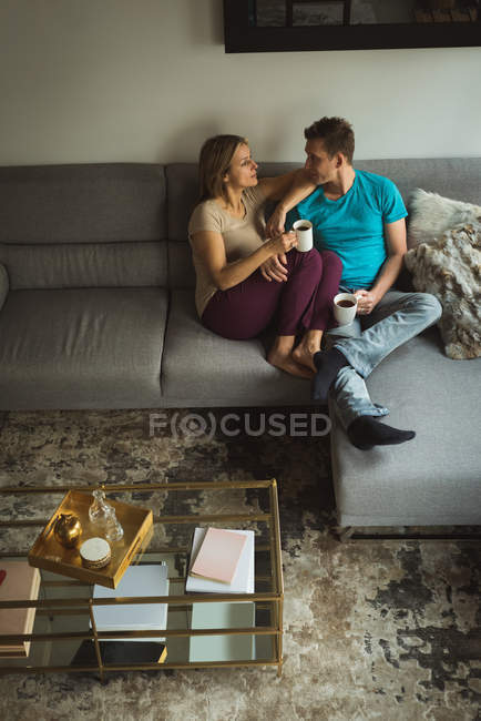 Pareja tomando café en la sala de estar en casa - foto de stock