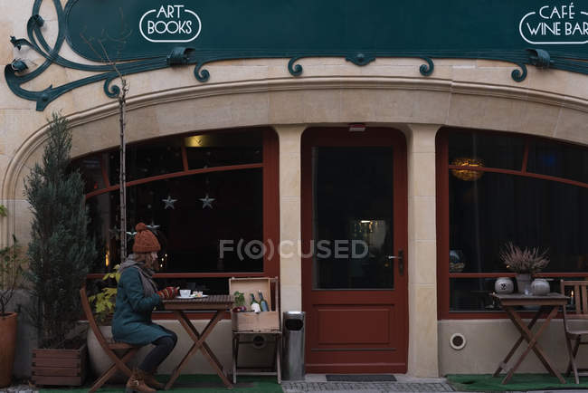 Женщина фотографирует сладкую еду с мобильного телефона в кафе на открытом воздухе — стоковое фото